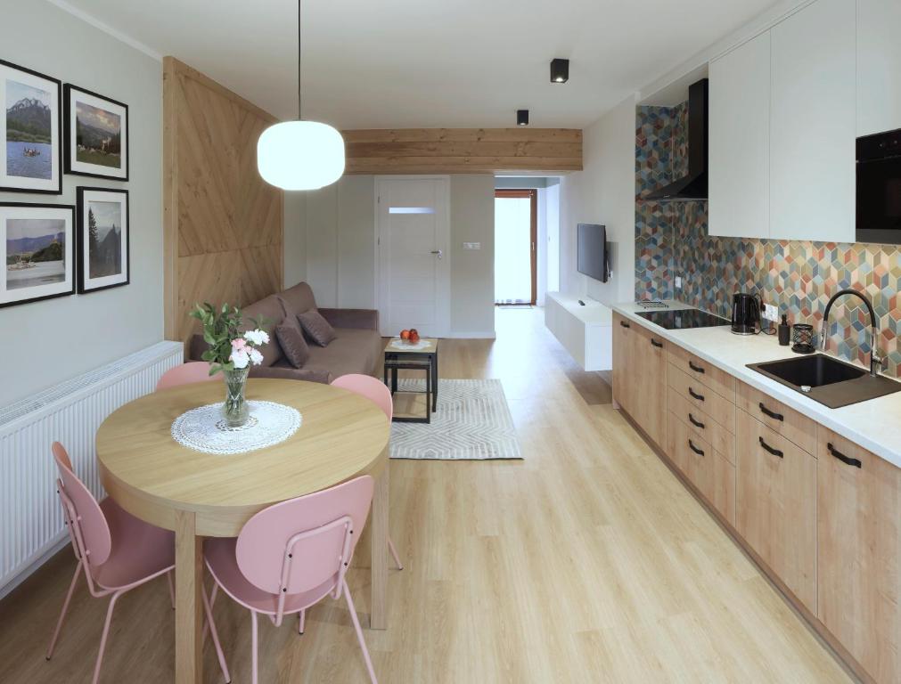 a kitchen and living room with a table and pink chairs at Apartamenty u Znańca in Sromowce Wyżne