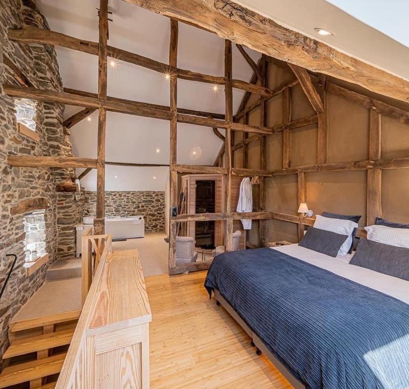 een slaapkamer met een bed en een stenen muur bij Paddock Lodge - Suites Wellness & Chambres d'hôtes in Stoumont