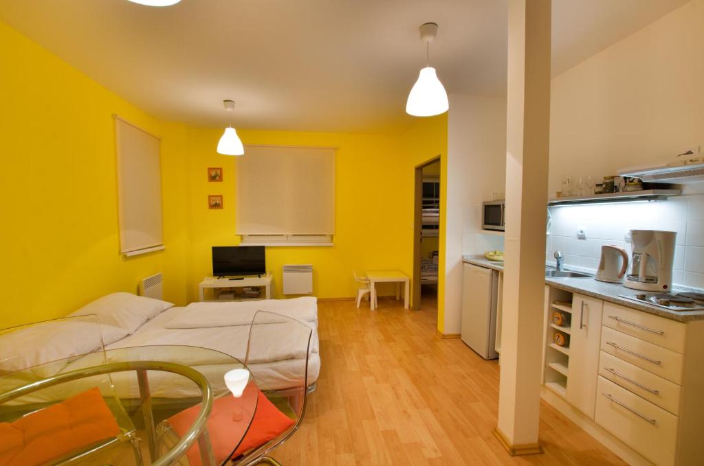 a room with a bed and a kitchen with yellow walls at Apartmán Orbit in Malá Morávka