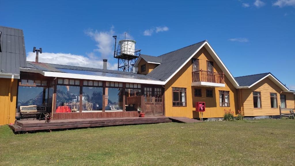 a large yellow house with a water tower at Hosteria Lago del Toro in Torres del Paine
