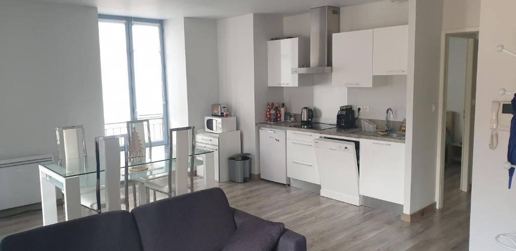 cocina con armarios blancos y mesa de cristal en Appartement T2 45 m² en centre-ville, en Ax-les-Thermes