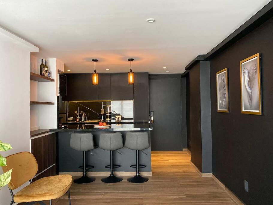 una cocina con armarios negros y taburetes de bar en Black Loft. Moderno y nuevo, súper ubicado., en Ciudad de México