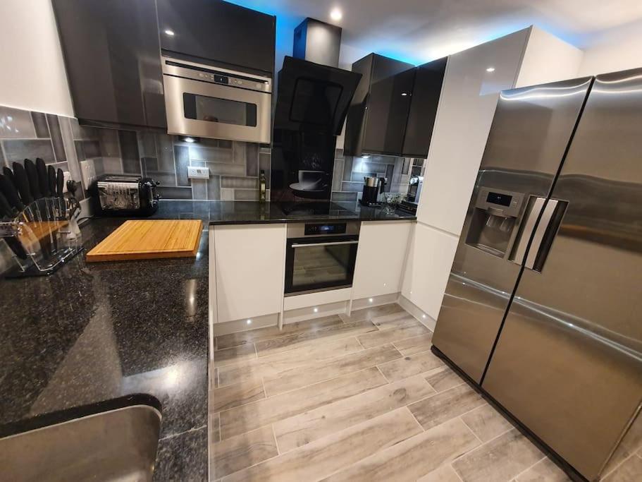 a kitchen with stainless steel appliances and black counter tops at Luton Town Centre Executive Apartment in Luton