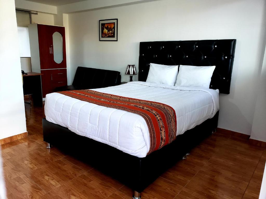 Hostal Cusco de mis Sueños في كوسكو: غرفة نوم بسرير كبير وكرسي