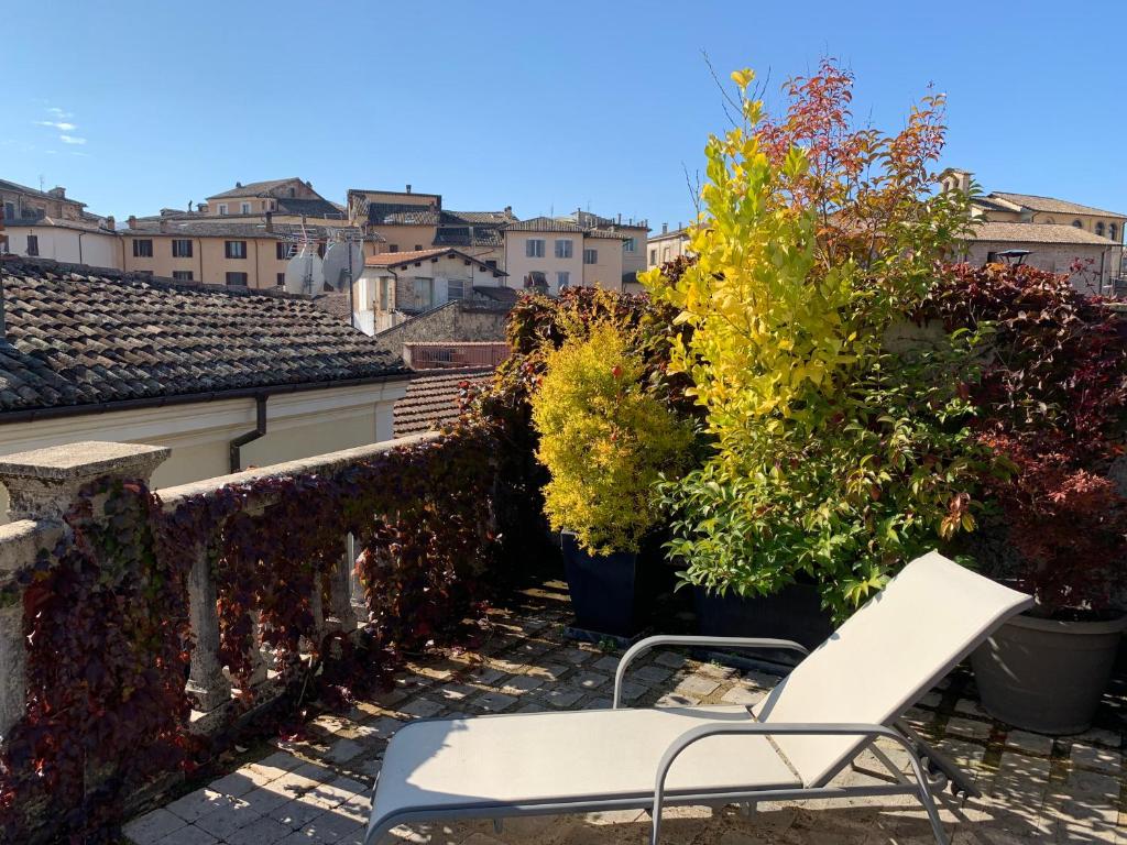 リエーティにあるPorta Conca Apartmentsの白い椅子、植物のあるバルコニー