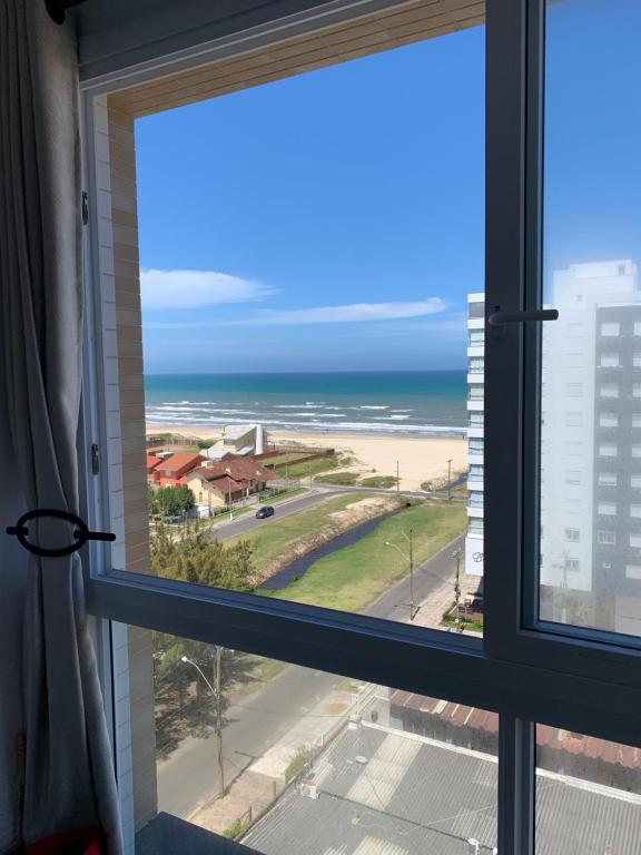 una ventana con vistas a la playa en Apartamento com vista para o mar, en Capão da Canoa