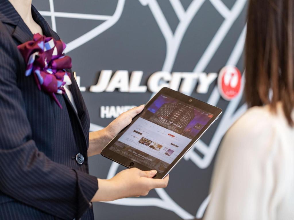 a man holding a tablet computer in front of a woman at Hotel JAL City Haneda Tokyo in Tokyo
