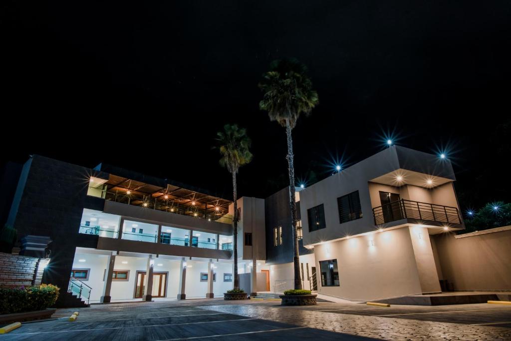 a building with palm trees in front of it at night at Hotel La Querencia in Río Verde