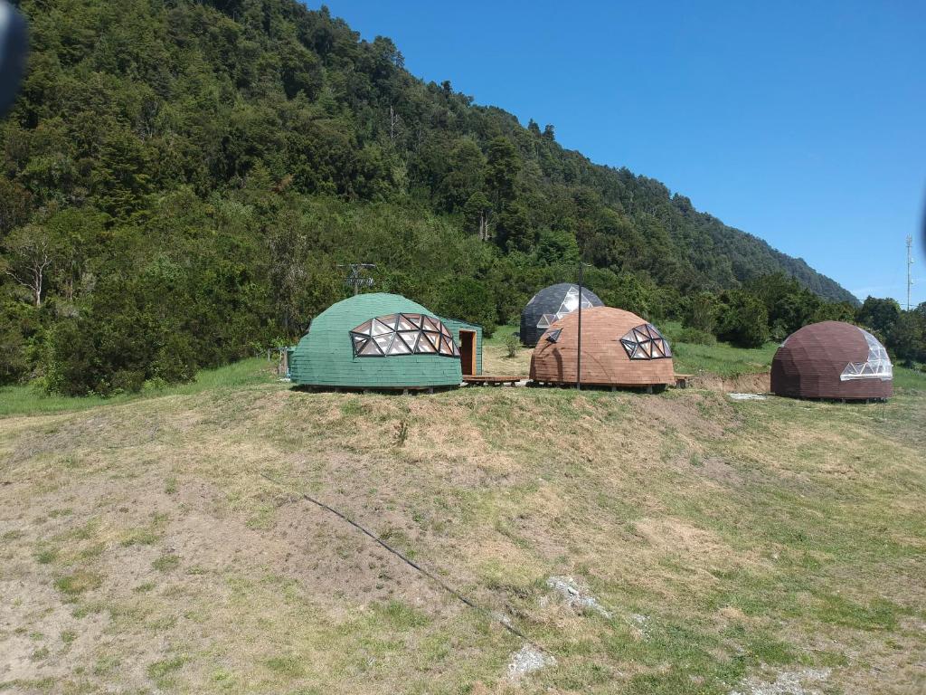 três cúpulas sentadas no topo de uma colina em Domos Trayenko em Ralún