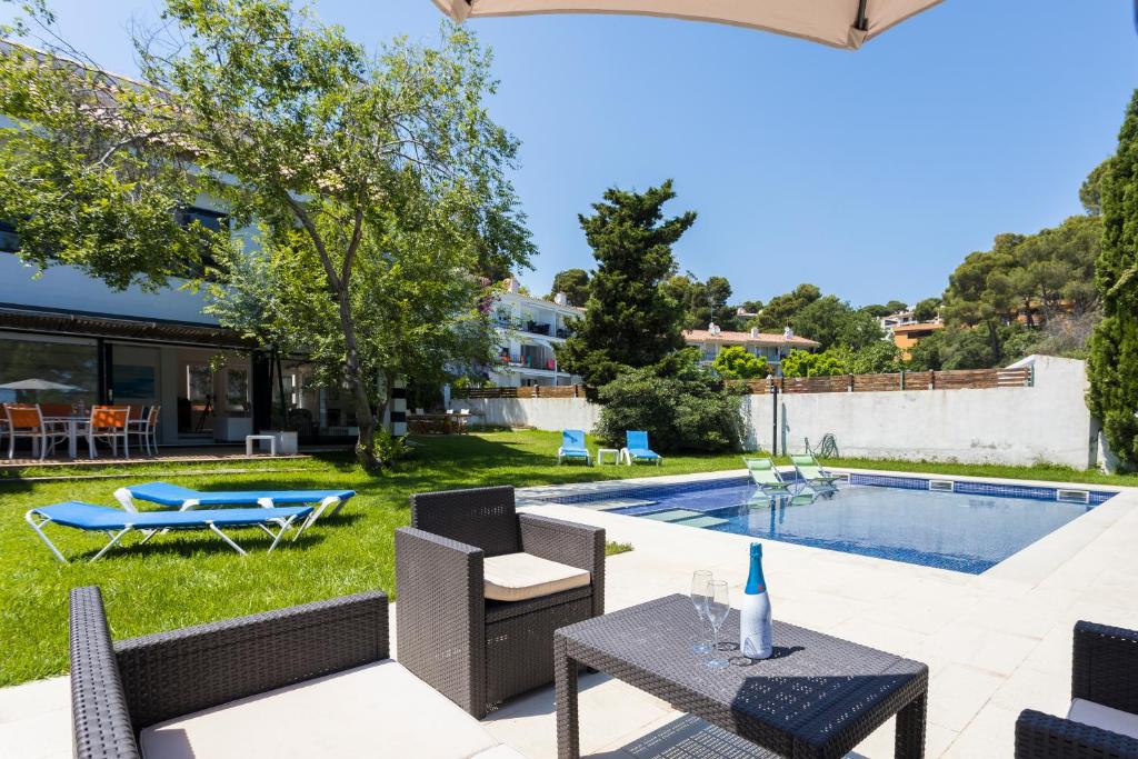 un patio con tavolo e sedie accanto alla piscina di Luxury villa in front of the sea ROSITA a Calella de Palafrugell