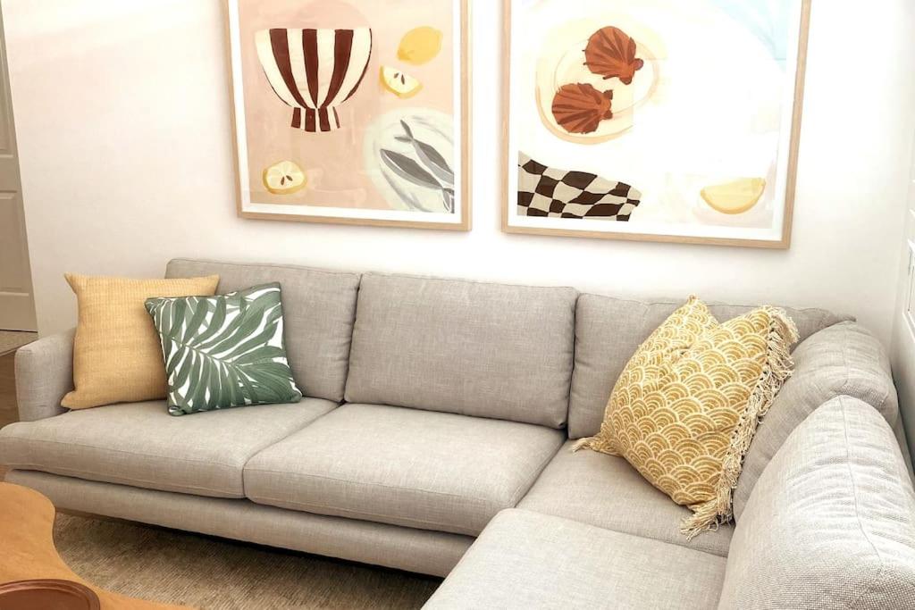 um sofá cinzento com almofadas numa sala de estar em Stay Peachy - Kiama em Kiama