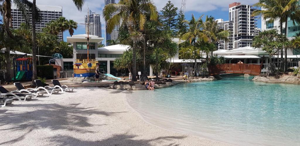 a swimming pool with chairs and palm trees and buildings at Crown Tower 25th Floor by Gold Coast Premium in Gold Coast