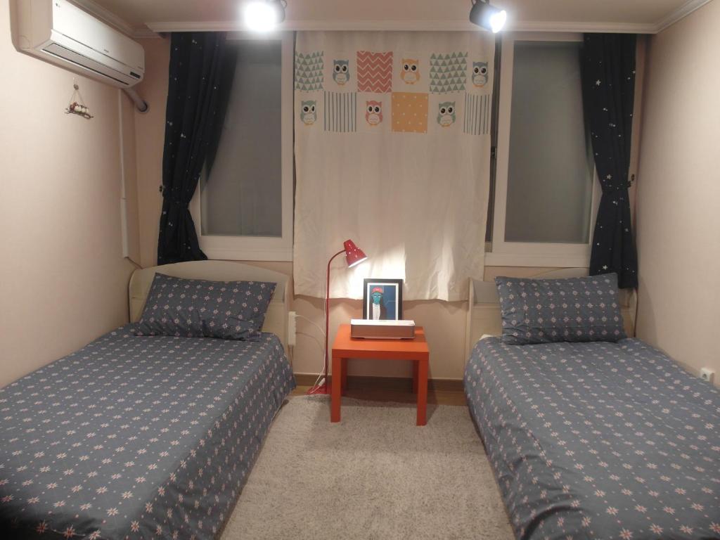 a bedroom with two beds and a table with a lamp at Kbook9 guesthouse in Seoul