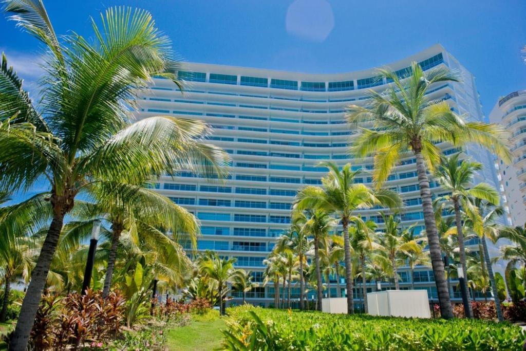 a tall building with palm trees in front of it at BONITO DEPARTAMENTO PENINSULA IXTAPA 02 Recámaras in Ixtapa