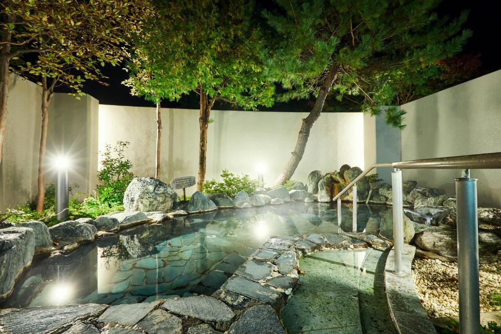 un bassin d'eau avec des rochers et des arbres dans l'établissement KAMENOI HOTEL Shiobara, à Nasushiobara