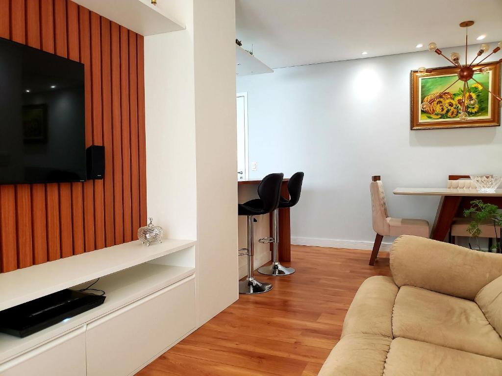 a living room with a couch and a television on a wall at Apê Novo em Sampa Prox do Tietê Plaza in Sao Paulo