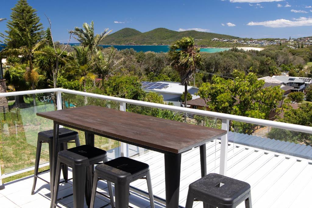 a wooden table and two stools on a balcony at Marine Drive in Forster