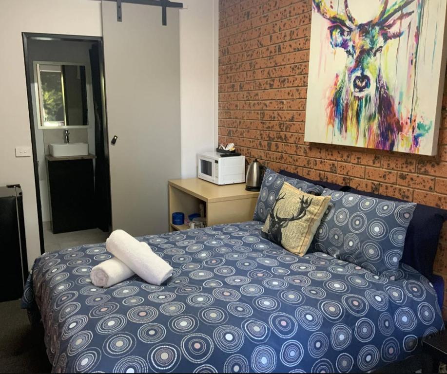 a bedroom with a blue bed and a brick wall at Merrijig Motor Inn in Merrijig