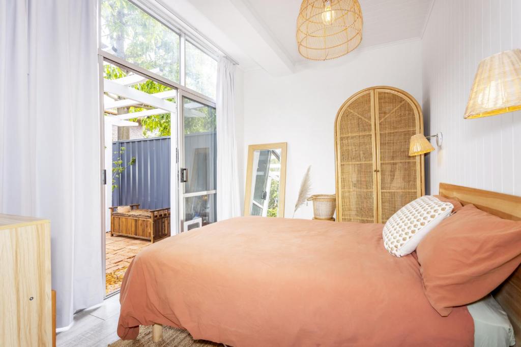 um quarto com uma cama e uma grande janela em Cottesloe Coastal Boho Retreat em Perth