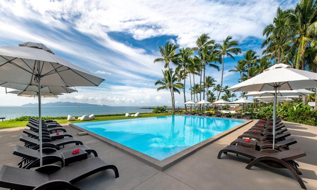パシフィック・ハーバーにあるThe Pearl South Pacific Resort, Spa & Golf Courseの- リゾート内のプール(椅子、パラソル付)