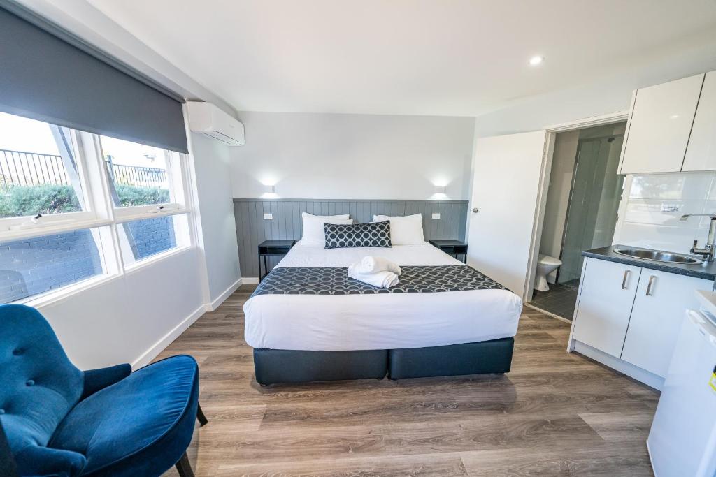 a bedroom with a large bed and a blue chair at Bega Motel in Bega