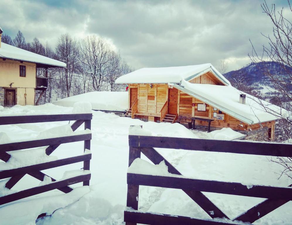 Eine schneebedeckte Holzhütte neben einem Zaun in der Unterkunft Guest House Kandaferi 2 in Elena