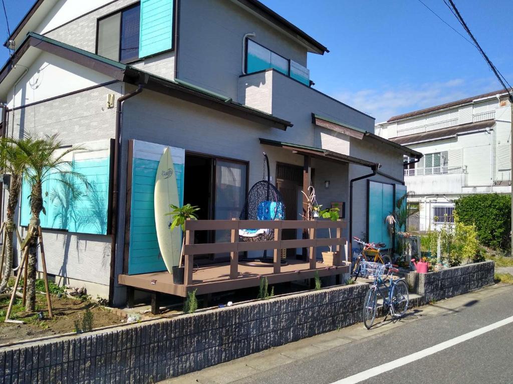 una casa con un porche con una tabla de surf en シーカレント　ゆな　CHIKURA, en Chikura