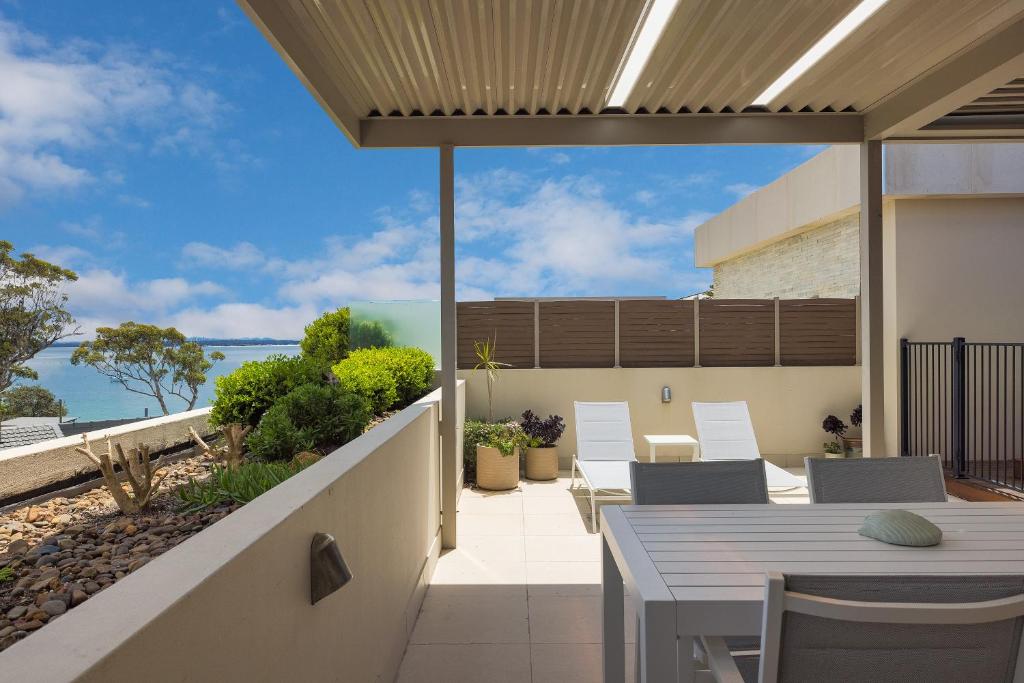 an outdoor patio with a table and chairs and the ocean at Aura 10 Shoal Bay in Shoal Bay