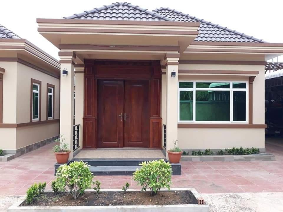 a house with a wooden door in front of it at Serei Saophoan Villa Homestay in Sisophon 