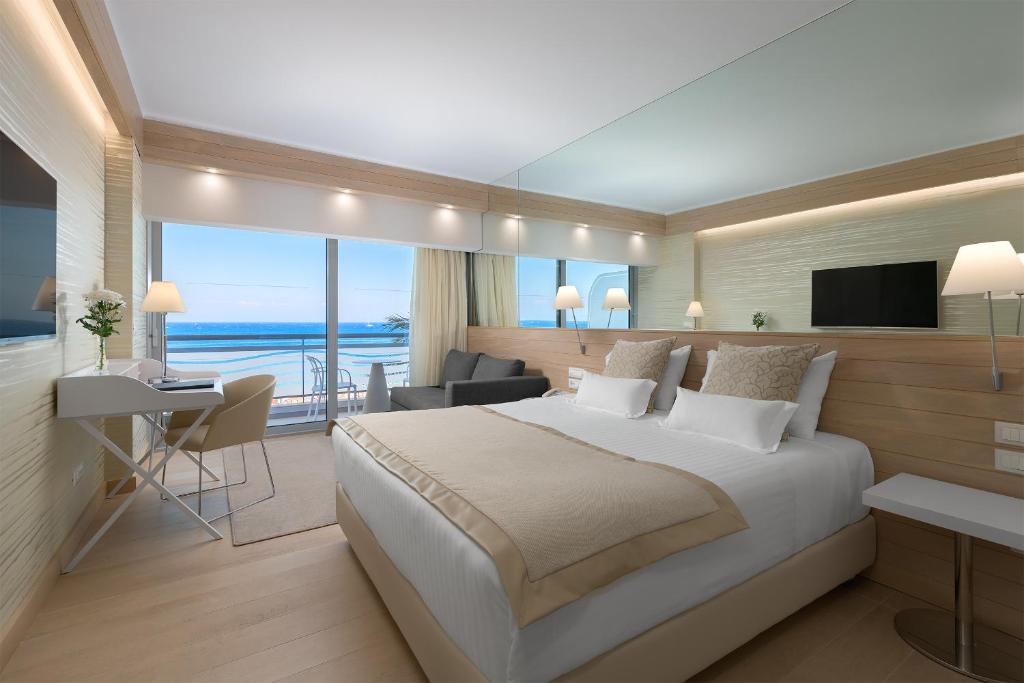 Schlafzimmer mit einem großen Bett und Meerblick in der Unterkunft Mediterranean Hotel in Rhodos (Stadt)