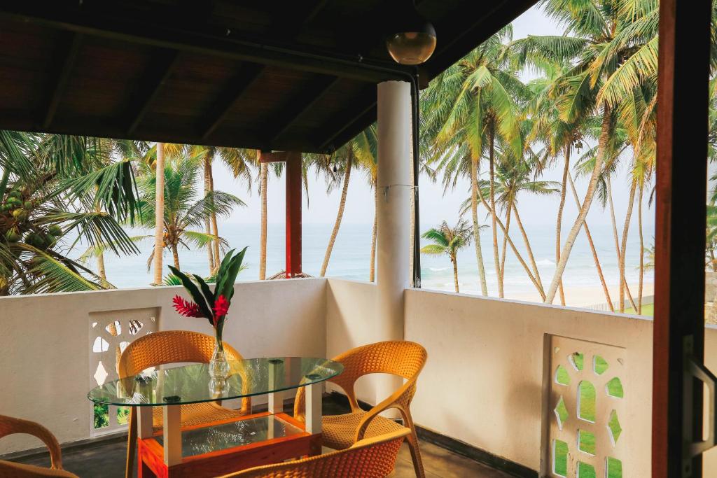 Habaraduwa CentralにあるParadise Beach House - 3 Bedrooms Apartment in Habaraduwaのビーチを望むバルコニー(テーブル、椅子付)