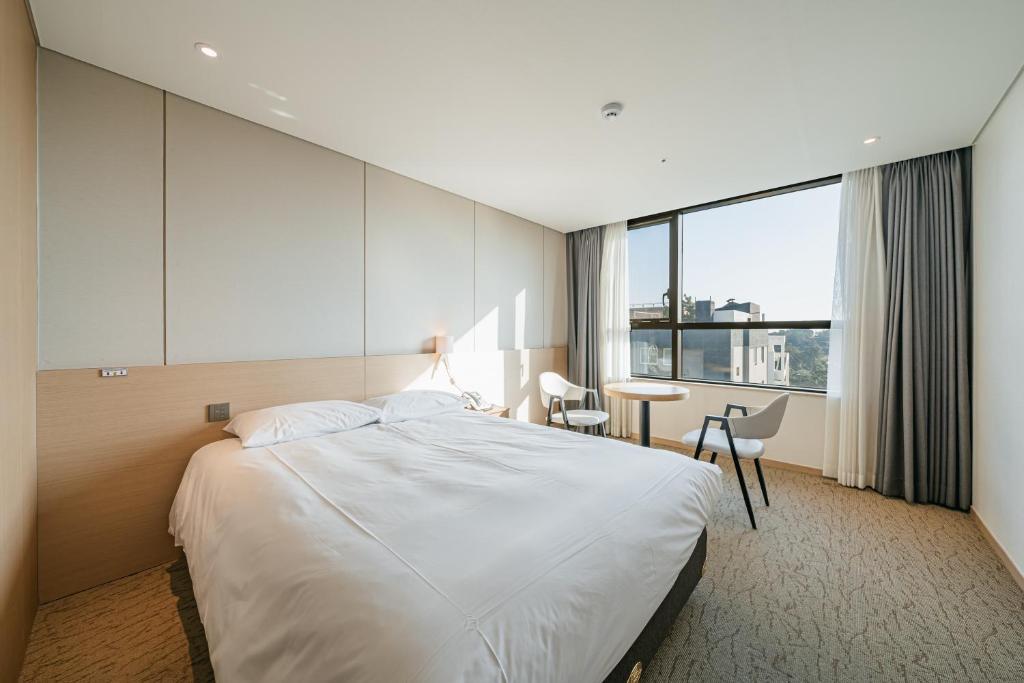 a hotel room with a large bed and a desk at Hotel Zinc in Seogwipo