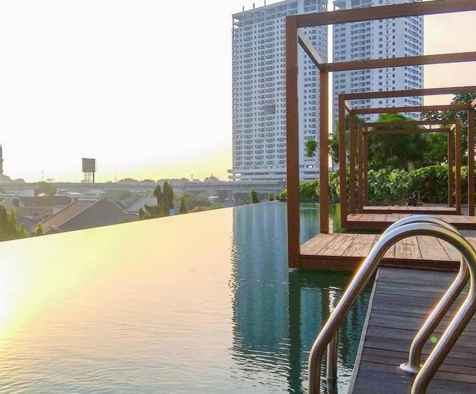 a swimming pool with a view of a building at Grand Kamala Lagoon by Hana Room in Bekasi