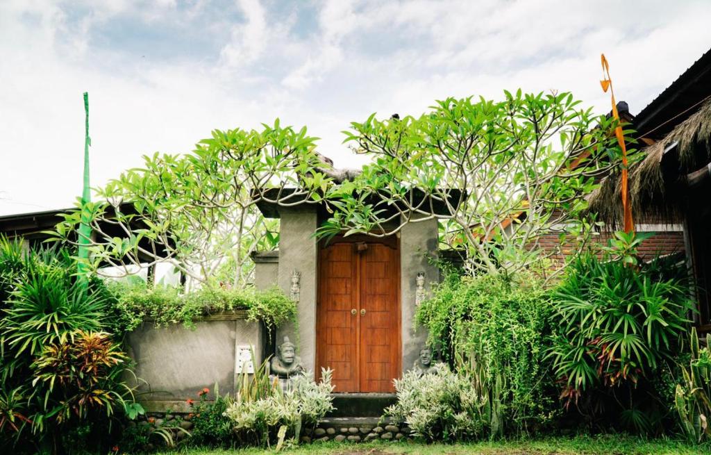 una casa con una puerta de madera y algunas plantas en The Asri Villas, en Jembrana