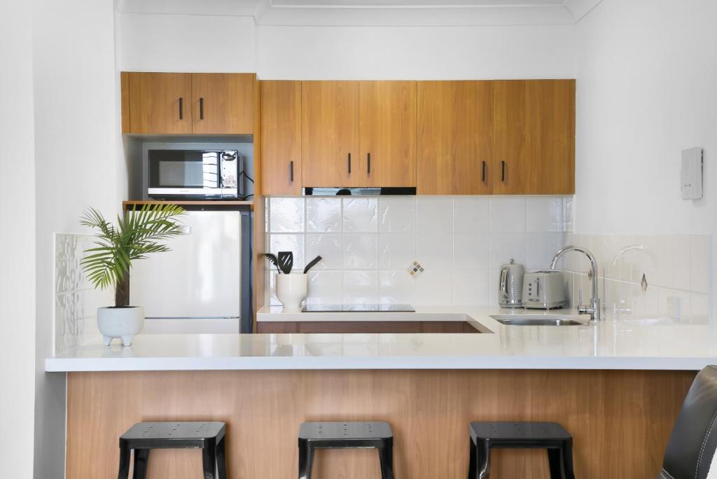 a kitchen with a white counter and some stools at 'Little Mermaid' beach apartment best location walk to beach and restaurants - sleeps 4 in Gold Coast