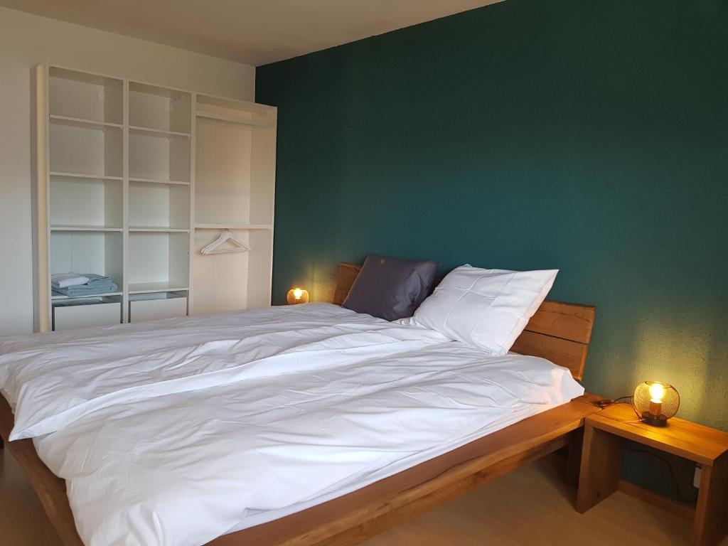 a bedroom with a large white bed with a green wall at Appartement Randogne in Crans-Montana