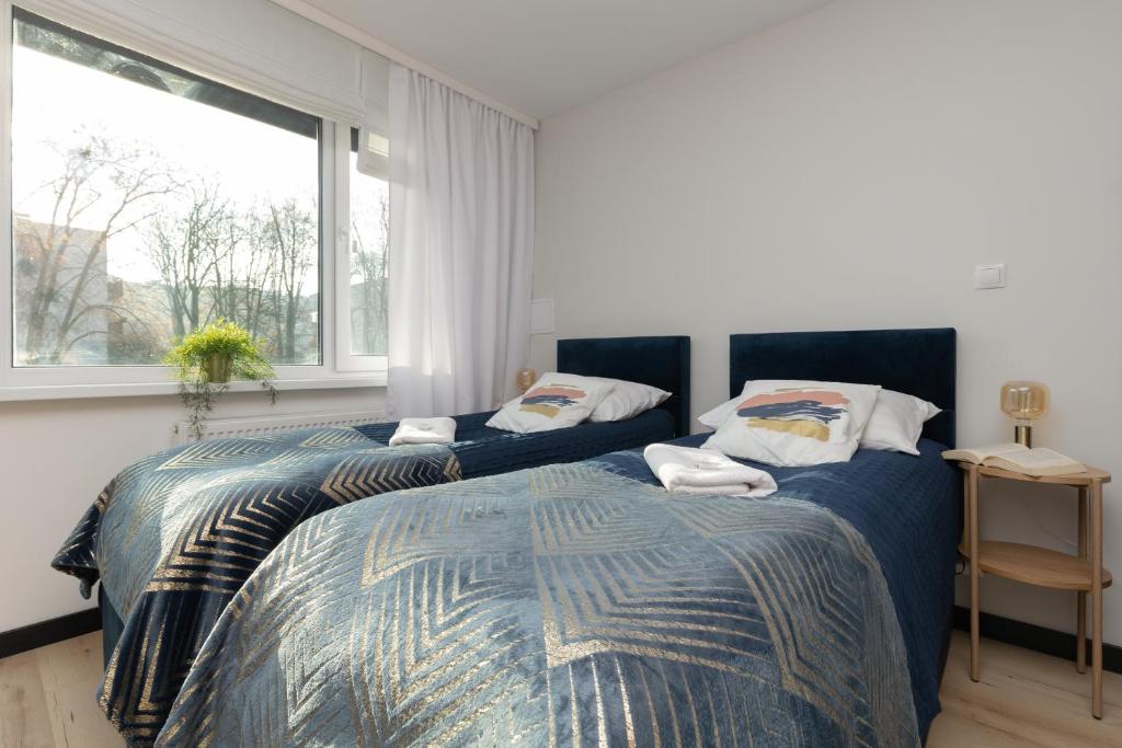 a bedroom with two beds and a large window at Warsaw Batorego Studio Apartments by Renters in Warsaw