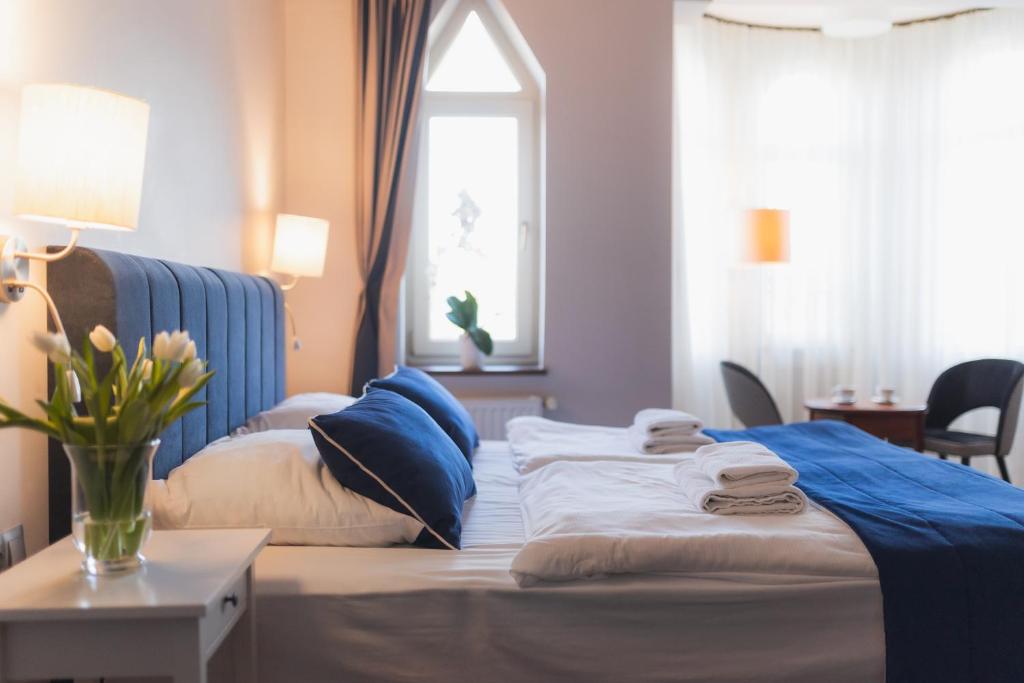um quarto com uma cama com almofadas azuis e uma janela em H Villa Herkules em Świnoujście