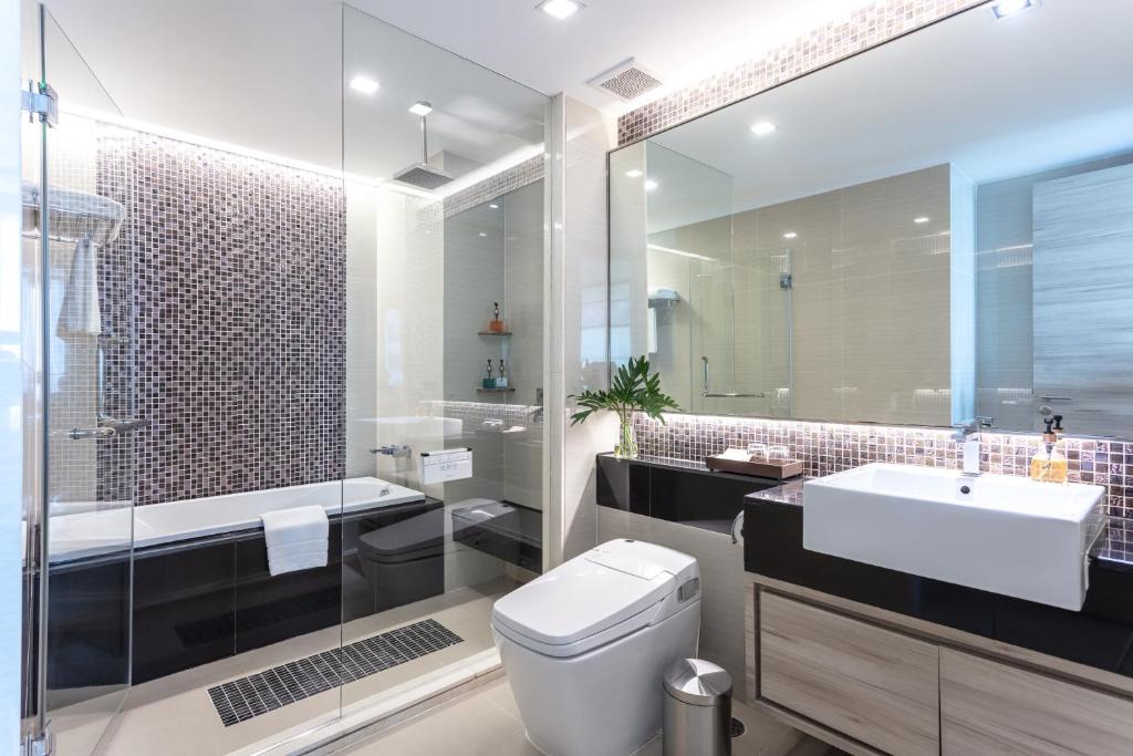 A modern bathroom with a glass-enclosed shower, soaking tub, toilet, and wide vanity.