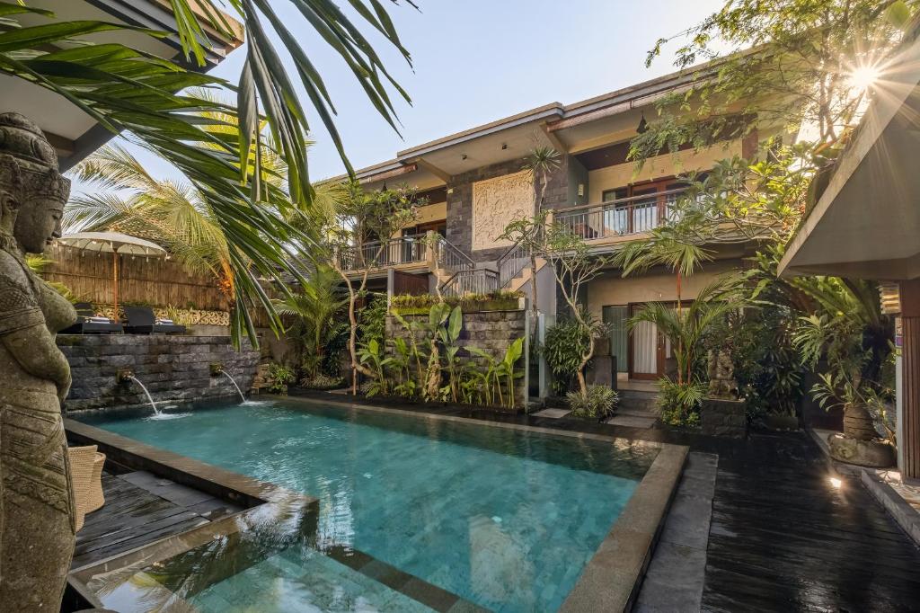 a swimming pool in front of a building with a resort at Kubu Rama Ubud Cottage in Ubud
