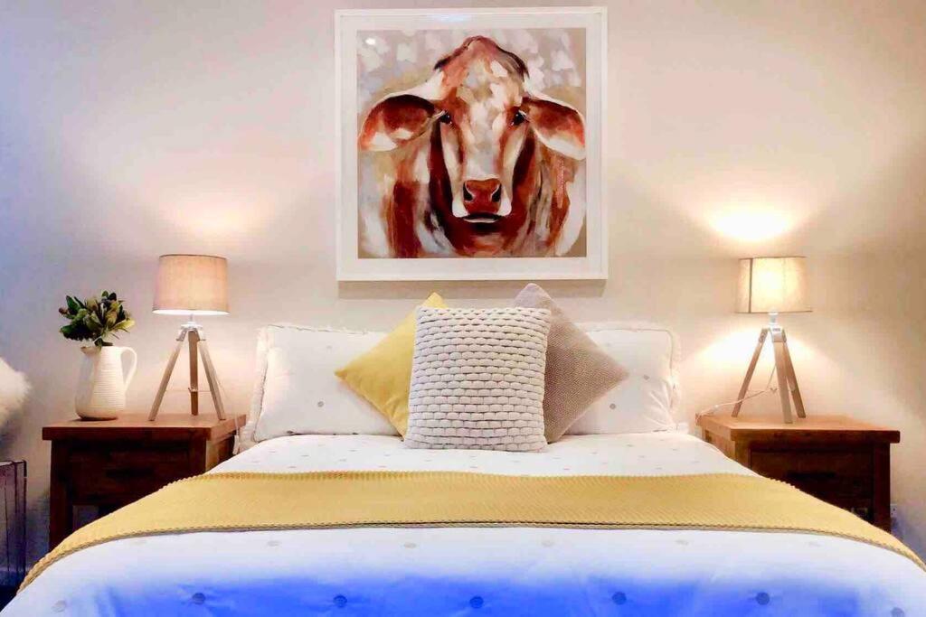 um quarto com uma cama com um quadro de uma vaca em 'TAMWORTH'S HIDDEN GEM’ 