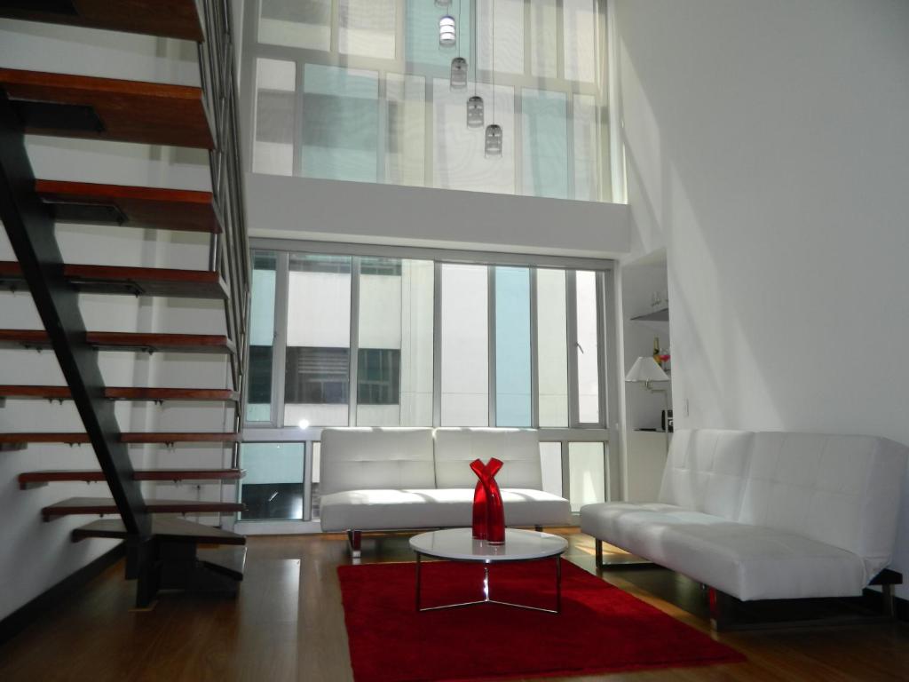 sala de estar con sofá blanco y alfombra roja en ItsaHome Apartments - Torre Aqua, en Quito