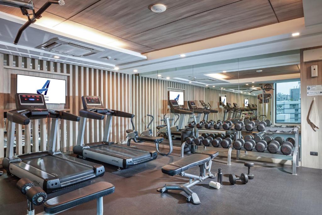 A compact gym with treadmills, benches, free weights and mirrored walls.