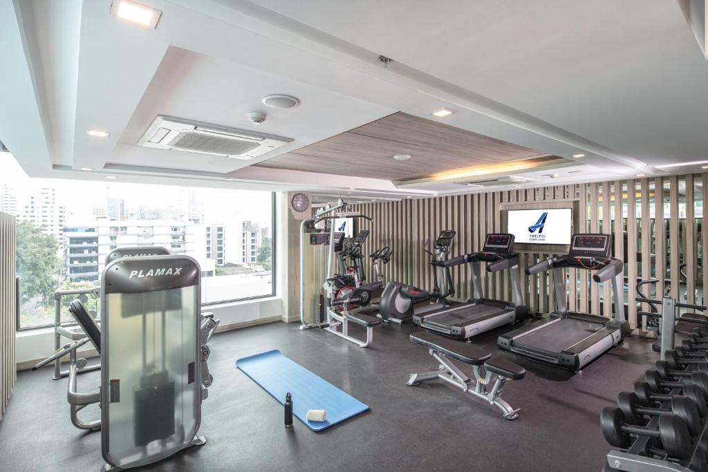A bright, windowed fitness room with cardio equipment, weights and a cable machine.