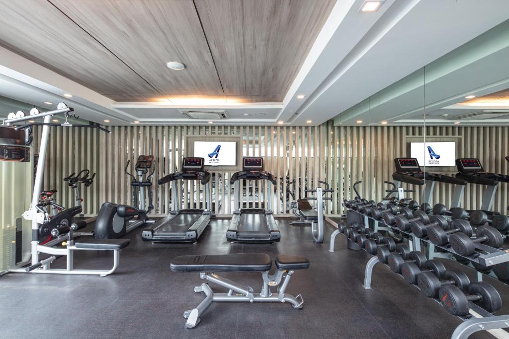 A mirrored fitness room centered on treadmills, bikes and a dumbbell rack.