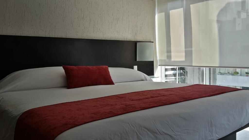 1 dormitorio con cama grande y almohada roja en Grupo Kings Suites -Monte Chimborazo 537, en Ciudad de México
