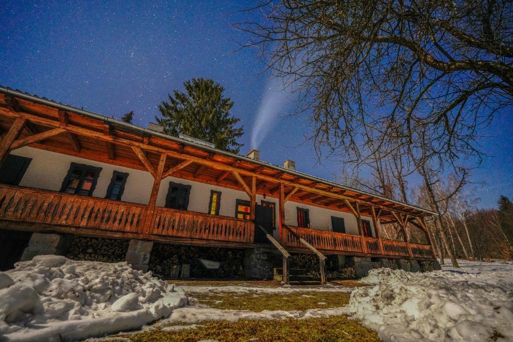 a large wooden building with snow in front of it at Dobrica Hunting Lodge in Bixad