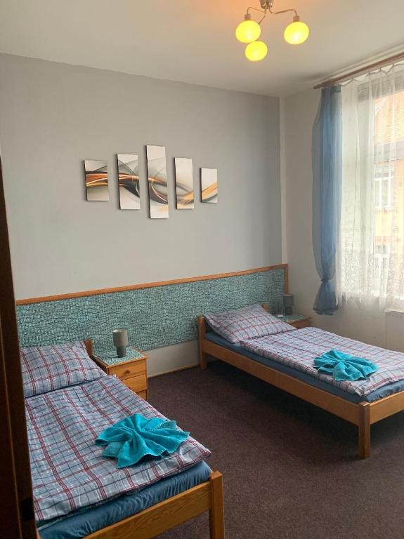 sypialnia z 2 łóżkami i oknem z niebieską pościelą w obiekcie Penzion Rajf w Karniowie