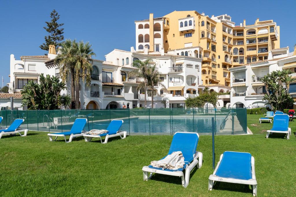a group of chairs on the grass in front of buildings at Beachfront Puerto Cabopino in Marbella