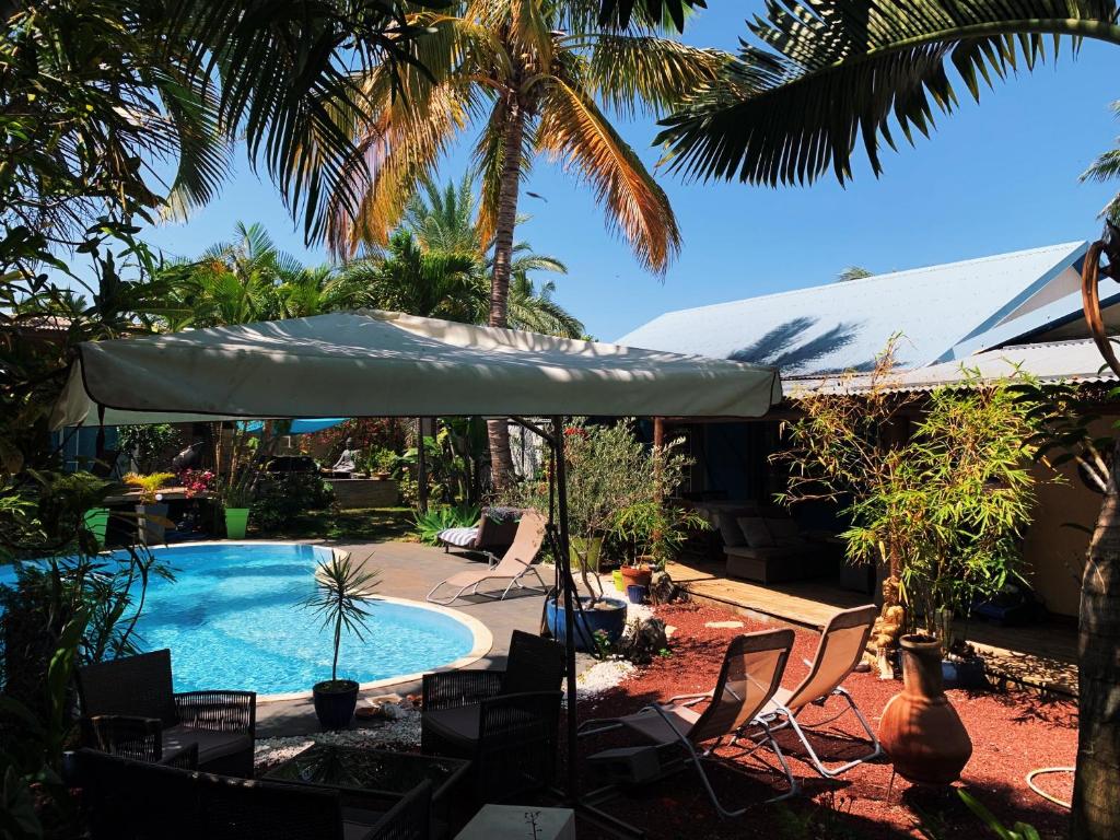 a swimming pool with an umbrella and chairs and a table at Casa Babalahy in Saint-Pierre